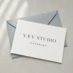 Porcelænshvidt VÆV STUDIO gavekort på en blågrå kuvert