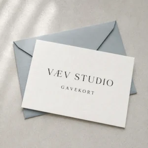 Porcelænshvidt VÆV STUDIO gavekort på en blågrå kuvert